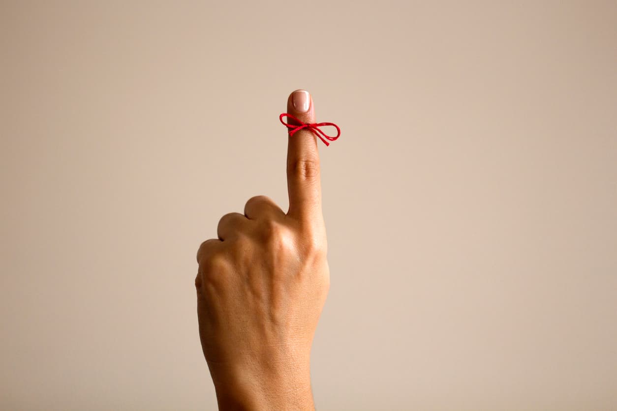 person holding up pointer finger with mini bow tied around it